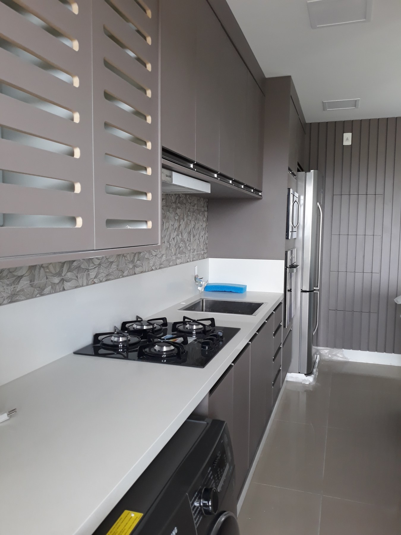 Detalhe da cozinha com portas vazadas em madeira, coifa e bancada em superfície clara